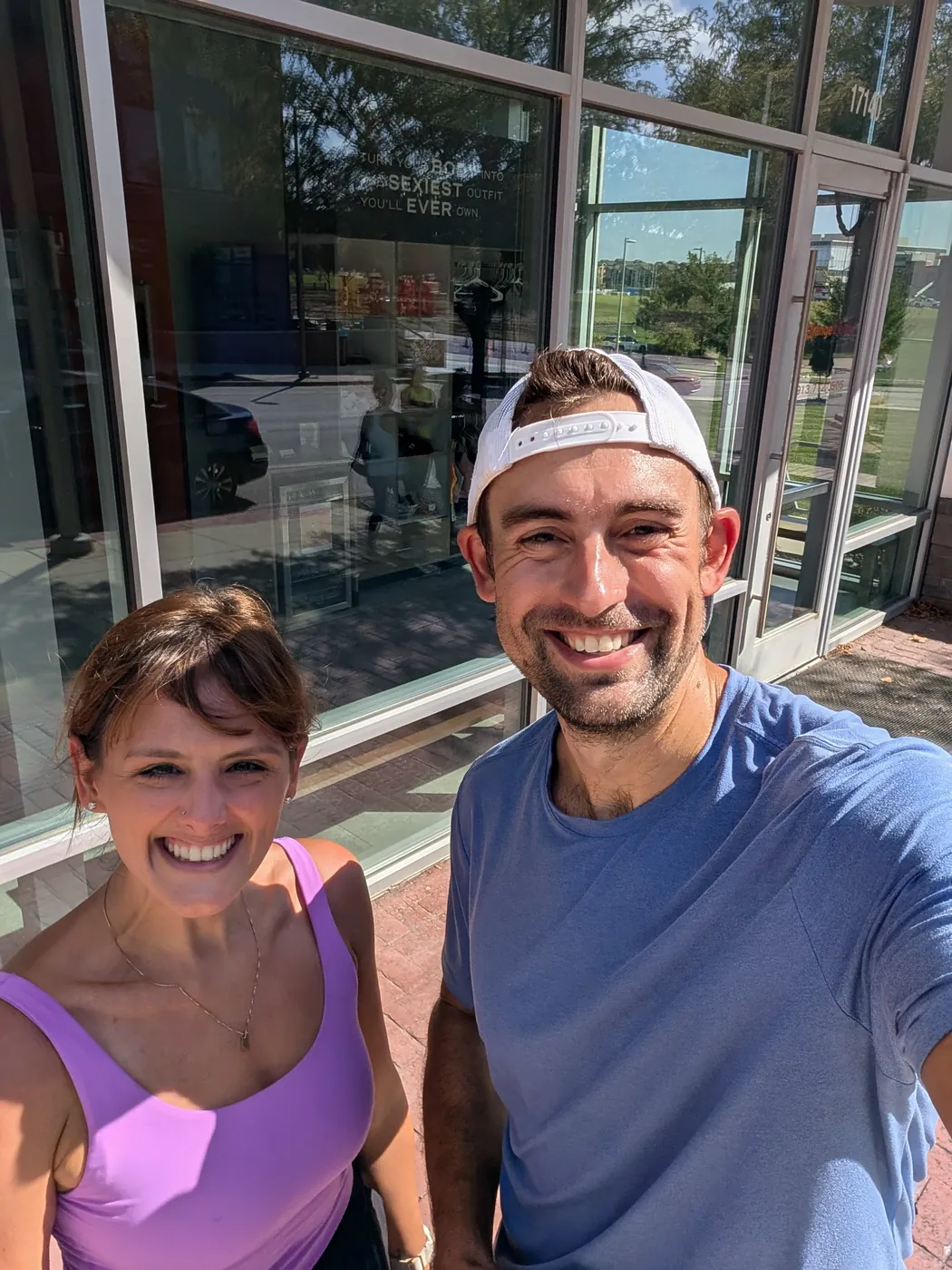 Natalie and me in workout clothes, sweaty and squinting into the sun outside the gym doors