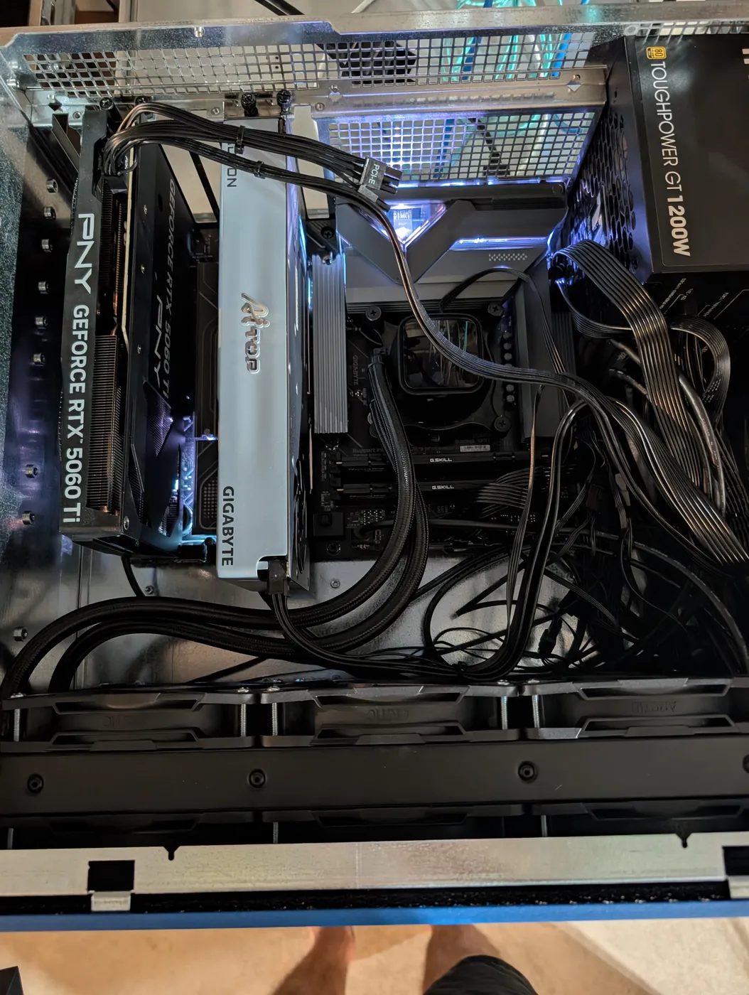 Top-down view inside the open case showing both graphics cards, the motherboard with a liquid cooler and G.Skill memory, a Toughpower GT 1200W power supply and a lot of black cables