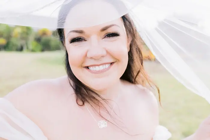 Close-up of a bride smiling under her veil, backlit outdoors