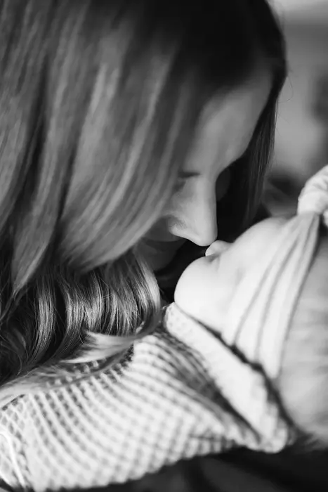 Black and white close-up of a mother leaning in nose to nose with her sleeping newborn