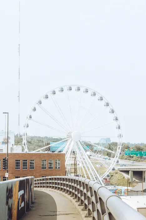 A white ferris wheel above the highway, seen from a curving overpass